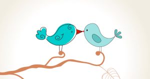 Two birds kissing on a branch in a tree.