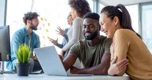 Small development team working together in front of a shared laptop